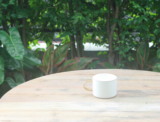 White coffee cup on a wooden table in a refreshing garden