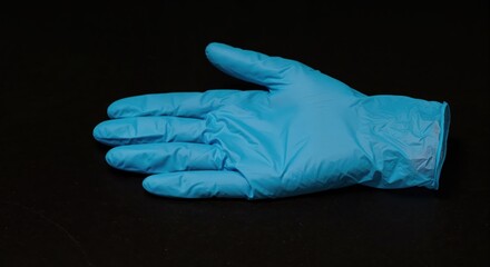 Gloved Hand: A single blue protective glove rests open, representing safety, hygiene, and medical procedures against a dark backdrop.