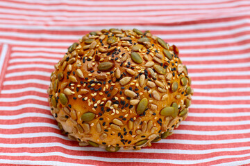 Round multigrain bread roll covered with pumpkin seeds, sunflower seeds, sesame, and black sesame.