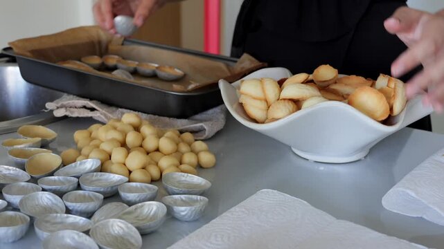 Crafting baked shells on countertop, Bakery scene with warm tones and baking tools visible, Preparing baked shells beside dough balls with tools and napkins on counter
