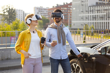 A couple wearing VR headsets while an electric vehicle charges in an urban setting.
