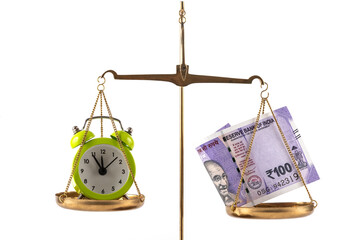 An alarm clock and a 100-rupee note of the Republic of India on a scale