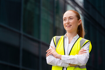 Young woman in safety vest posing in front of modern office building