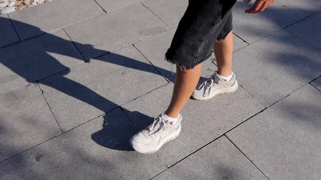 Boy strolling on patterned pavement, Shadow and steps during casual urban walk, Child exploring city streets wearing comfortable summer footwear and observing