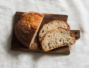 Sourdough homemade tartine bread on a wooden cutting board on a light background, top view
