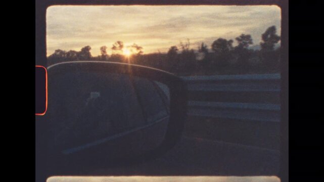 Golden hour sunset seen from a moving car with reflection in side mirror shot on retro 8mm film