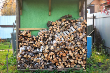 A stack of firewood in a woodshed outside
