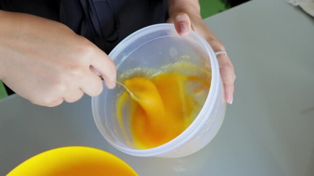 Bright orange egg mixture preparation, Vivid orange eggs combined in plastic bowl for baking, Energetic home baking scene with eggs blended in plastic dish on countertop