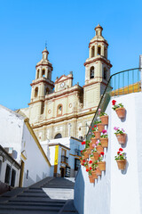 village street leading up to the church of Our Lady of the Incarnation against a blue sky in olvera,cadiz,spain