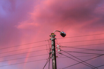 Atardecer en la ciudad un poste de luz bajo un cielo rosa y púrpura.