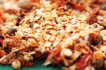 An extreme close-up, top-down macro shot of a pile of dry, yellow chili pepper seeds. The seeds fill the frame, creating a detailed texture background.