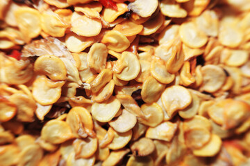 An extreme close-up, top-down macro shot of a pile of dry, yellow chili pepper seeds. The seeds...