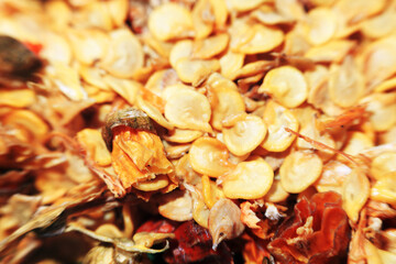 An extreme close-up, top-down macro shot of a pile of dry, yellow chili pepper seeds. The seeds fill the frame, creating a detailed texture background.