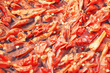 An extreme close-up, top-down view of dried red chilies and seeds soaking in water, creating a vibrant and detailed food texture background.