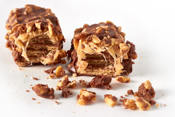 Two pieces of wafer-caramel bar sprinkled with nuts and covered in chocolate