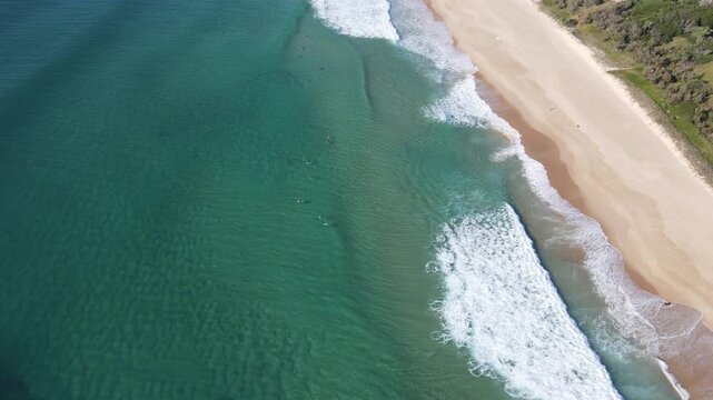 Drone aerial over clear water at coolum beach with surfers on waves