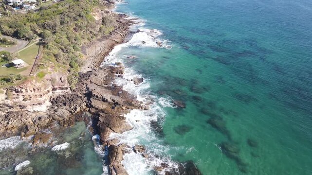 Drone aerial moving over a coastal cliff area on a sunny day in Coolum Beach