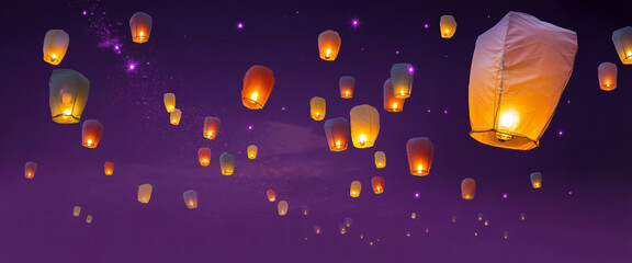 A multitude of glowing sky lanterns ascend into the deep purple night sky, creating a magical and festive atmosphere