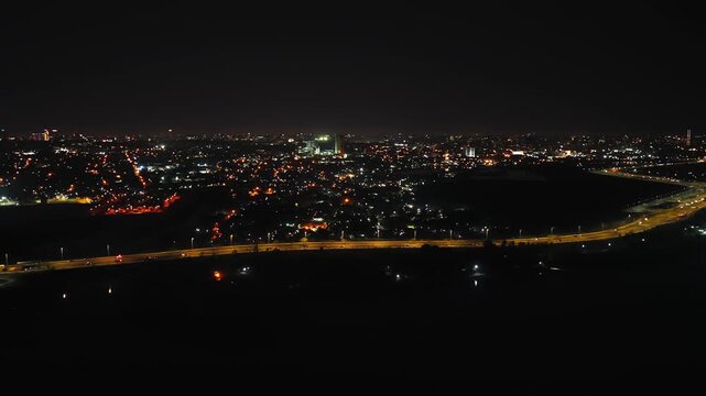 A sweeping aerial nightscape of Asuncion, Paraguay showcasing the illuminated city skyline and Costanera avenue from Heroes of Chaco bridge under a starry sky, captured in high definition.