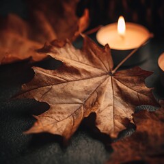 Warm glowing candle light illuminates a textured brown autumn maple leaf close up