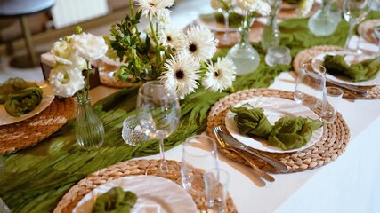 A beautiful banquet table with plates and dishes decorated with floristry and white floral decor. Wedding celebration, family holiday, family birthday