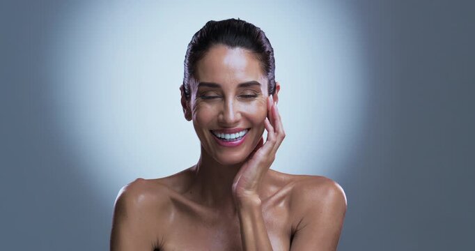 Face, woman and laughing in studio with skincare for collagen, retinol or anti aging benefits. Smile, mature or female person with spotlight for beauty, dermatology or smooth skin on gray background.
