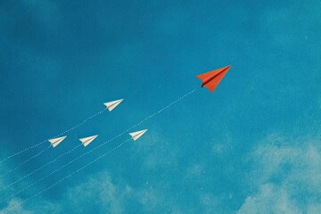 A red paper plane leads a formation of white planes against a blue sky