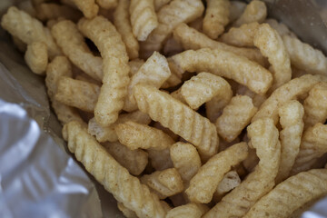 Close up of delicious, crunchy prawn cracker snack inside bag. tasty, savory junk food has ridged texture, ready to eat for salty, unhealthy, but enjoyable treat