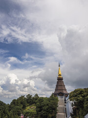 Fototapeta premium Majestic Phra Mahathat Naphamethanidon pagoda at Doi Inthanon National Park, Thailand. Golden spire against dramatic clouds, surrounded by vibrant mountain flora. Serene spiritual landmark.