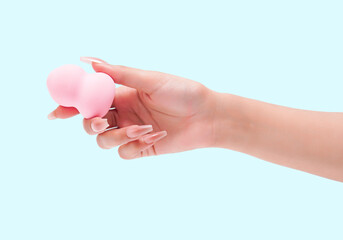 Female hand with manicured nails holding a pink beauty blender makeup sponge