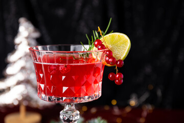Christmas Sangria cocktail in elegant wine glass and festive decor on dark table close up, festive cranberry cocktail with lime