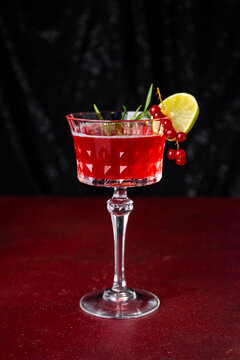 Christmas Sangria cocktail in elegant wine glass on dark table vertical photo, festive cranberry cocktail with lime
