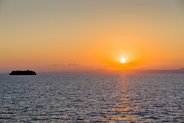 Obraz premium Silhouette of a cruise ship at sea during an orange sunset sky over the horizon