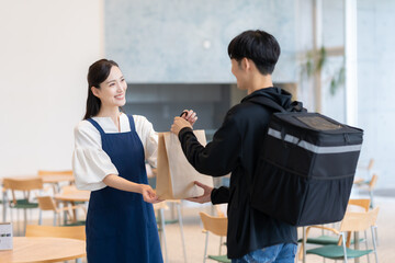 カフェで働く若い女性と配達員