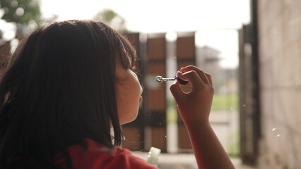 Little Girl Blowing Soap Bubbles Outdoors on a Sunny Day