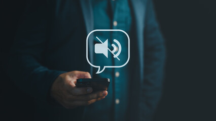 Person holding smartphone with mute sound icon, representing digital silence, notification control,...