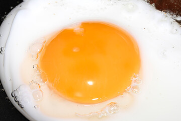 Close up of Fresh egg frying in a pan with golden yolk