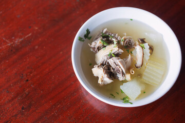 Chicken soup in a white plate placed on a wooden table