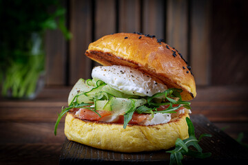 Bun breakfast sandwich with salt salmon, cream cheese and poached egg
