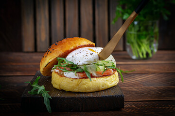 Bun breakfast sandwich with salt salmon, cream cheese and poached egg