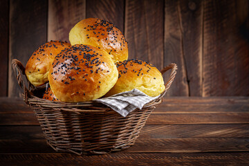 Homemade freshly baked plain golden brown soft hamburger buns topped with sesame seeds against wooden background. Homebaking