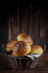 Homemade freshly baked plain golden brown soft hamburger buns topped with sesame seeds against wooden background. Homebaking, freshness, bbq concept