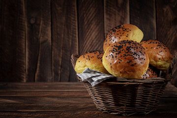 Homemade freshly baked plain golden brown soft hamburger buns topped with sesame seeds against wooden background. Homebaking, freshness, bbq concept