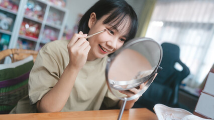 Young adult asian woman makeup and face skincare before mirror at home