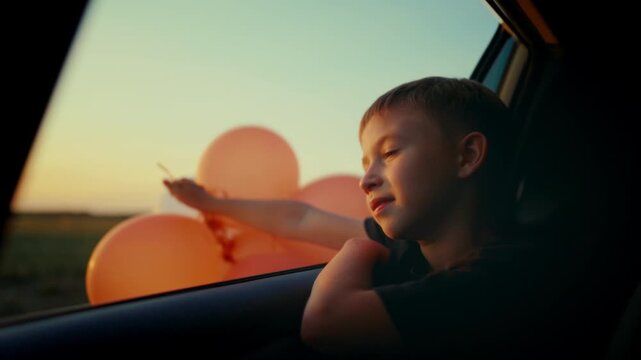 Little child dreaming of future, sitting inside car moving in nature, portrait. Happy childhood moments, having fun and joy, beautiful sunset or sunrise shine on cute face of carefree preschool boy