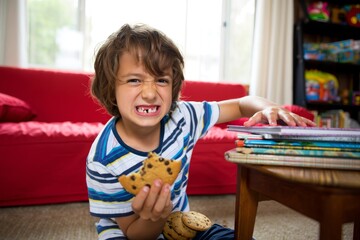 Joyful Boy Enjoying Cookies While Surrounded by Colorful Toys and Books in a Bright Living Room