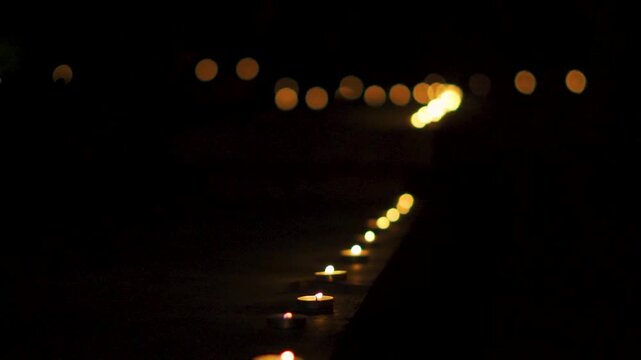 Row of lit Diyas with flickering flames against dark background. Closeup shot of the Diya on the wall during the Diwali festival in India. Indian festival.
