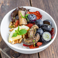 Delicious and healthy salad with fresh fruits and vegetables in a white bowl.