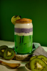 Healthy green and purple layered smoothie with kiwi slices, lime, and mint leaves for summer vibes.