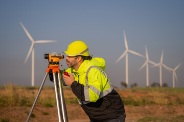 Engineer working in front of wind turbines for checking wind turbines of the field during beautiful sunset. Alternative energy concept.